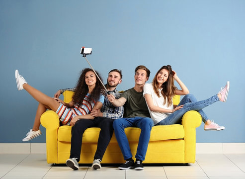 Young Cheerful Friends Taking Selfie On Yellow Sofa In The Room