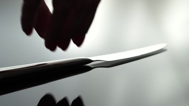 A knife beeng placed on a reflecting table, shallow focus