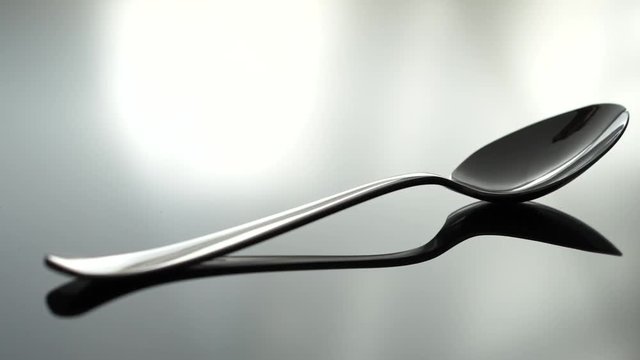 A spoon beeng placed on a reflecting table, shallow focus