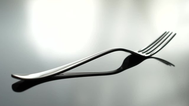 A fork beeng placed on a reflecting table, shallow focus
