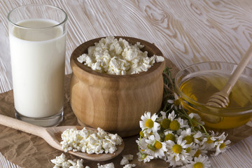 Honey, cottage cheese, glass with milk and chamomile flowers