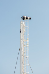 Frayed windsock in moderate wind against blue sky with few clouds