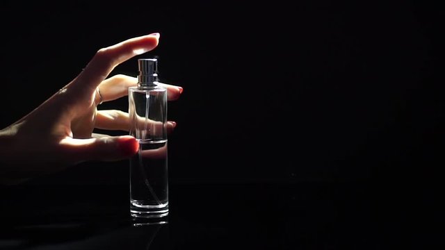 A perfume being sprayed by a beautiful girl hand, slow motion video