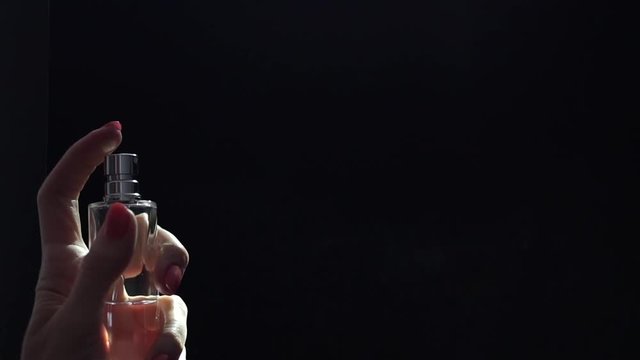 A perfume being sprayed by a beautiful girl hand, slow motion video