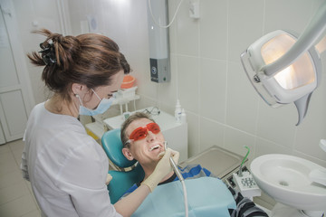 female dentist doctor holding dental drill, patient in the dentist's chair