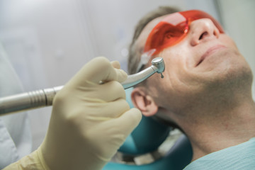 closeup dental care concept stomatology inspection. the patient lies in a chair in dentistry in front of him a hand with drill