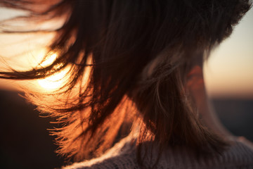 Close-up woman's hair at sunset on back view. Tender moment of watching sun in summertime
