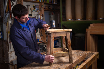 Carpenter restoring Wooden Stool Furniture in his workshop.