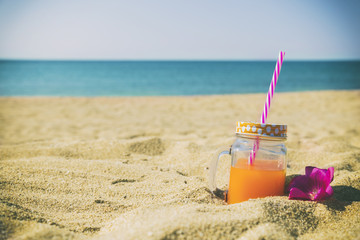 Orange juice in jar on the beach.

