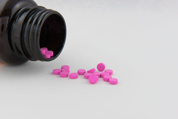 Pink drug tablets in bottles and white background