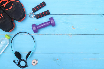 Flat lay shot of Sport equipment. Sneakers, water, earphones and phone on wooden background. Focus is only on the sneakers.