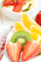 Bowl with fruit salad - pieces of strawberry, oranges, and kiwi