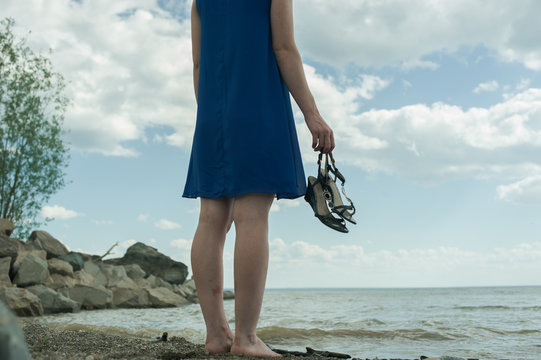 девушка босяком стоит на берегу моря и смотрит вдаль . barefoot girl standing on the beach and looks into the distance