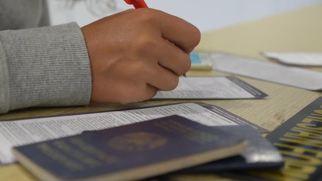 Female Hand Fills Customs Declaration with Passport at Airport