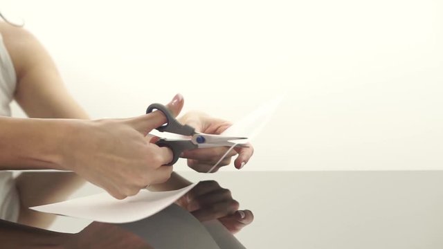 Female hands cutting a sheet of paper with scissors