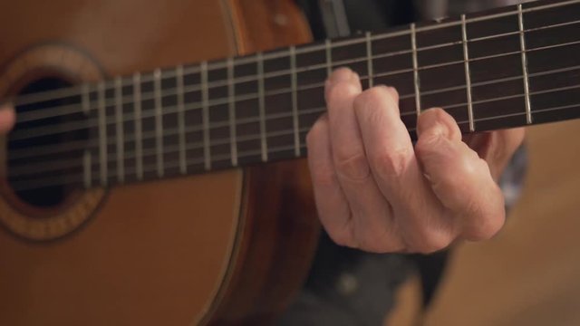 Close-up Of Old Retired Senior Man Hands Playing A Classical Acoustic Guitar. Elderly People Enjoying Retirement Lifestyle Concept. Handheld.