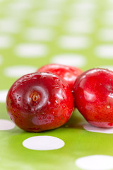Three cherries on the table cloth with blurred background