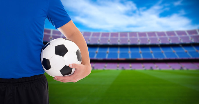 football player holding soccer ball on field of big stadium