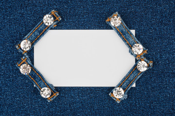 Business card with four straps jeans with rhinestones, lies on the light denim