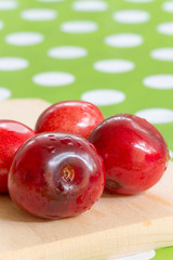 Three cherries on the table cloth with blurred background