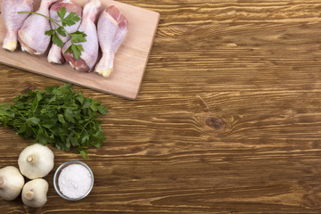 Fototapeta na wymiar raw chicken drumstick on the board with salt, garlic, parsley