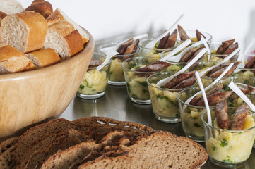 Buffet / Buffet mit verschiedene Brotsorten und in Glaesern servierter Kartoffelsalat mit Bratwurst.