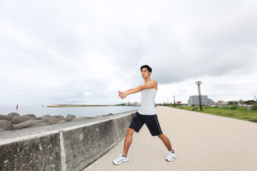 海岸でストレッチをする男性