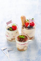 Homemade italian dessert tiramisu with strawberries, mint and cocoa in glass jars, closeup
