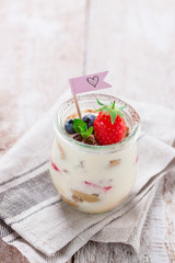 Homemade italian dessert tiramisu with strawberries, mint and cocoa in glass jars, closeup.