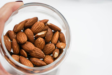 close up a transparent bowl of almonds in hand