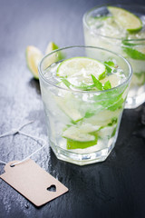 Fresh juicy mojito in glasses on a dark stone background, closeup.