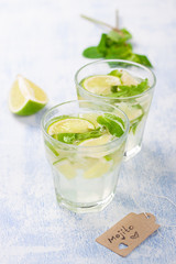 Fresh juicy mojito in glasses on a dark stone background, closeup.