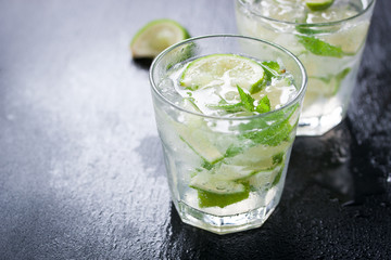 Fototapeta premium Fresh juicy mojito in glasses on a dark stone background, closeup.