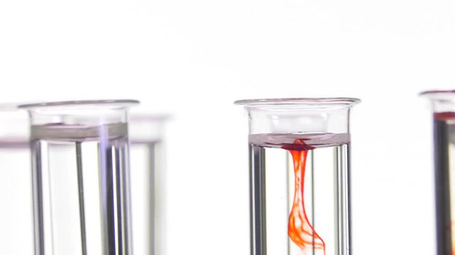 pipette depositing drops of red dye in rotating test tubes