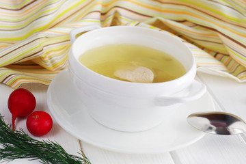 Chicken soup in a white bowl on wooden table