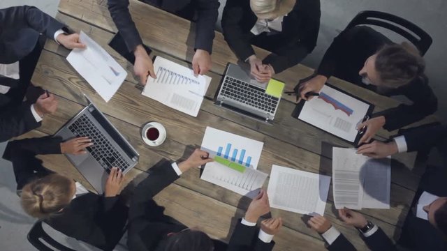 Business people discussing the charts and graphs showing the results of their successful teamwork