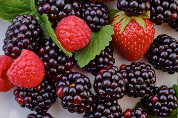 Heap of blackberries, strawberries and raspberries with mint leaves