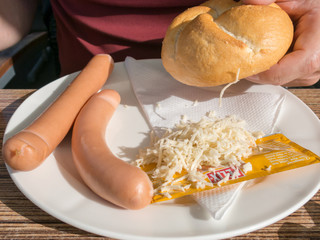 Two Frankfurter or Wiener sausages with bread roll and horseradish on a plate -  famous snack in Austria and Germany