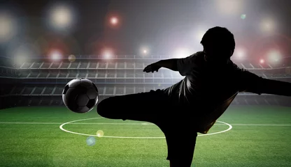 Foto op Plexiglas silhouette football player kicking the ball with stadium background © phonlamaiphoto