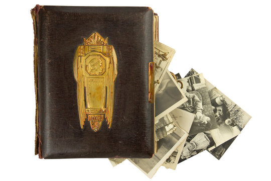 Vintage photo album (circa 1900) with buckle, brass engraved decoration and falling out retro photos (circa 50s) isolated on white