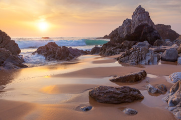 Fantastische große Felsen und Meereswellen bei goldenem Sonnenuntergang
