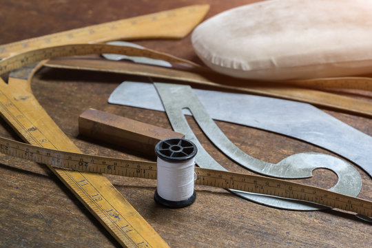 Measuring and cutting textile or fine cloth. Work table of a tailor. Gold scissors and black fabric. - Powered by Adobe