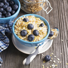 pair of blue ceramic bowls full  breakfast cereal with fresh blueberries and milk