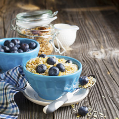 pair of blue ceramic bowls full  breakfast cereal with fresh blueberries and milk