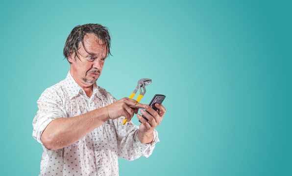 nasser Mann mit Wasserpumpenzange sucht auf Smartphone nach Hilfe