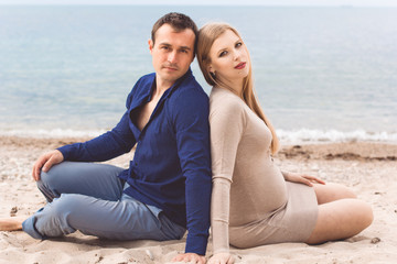 Fototapeta na wymiar Man and pregnant woman are resting on the beach