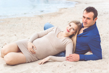 Fototapeta premium Man and pregnant woman are resting on the beach