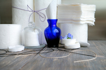 White kitchen paper towel, toilet paper, paper tissues ,cotton disks on a dark wooden table