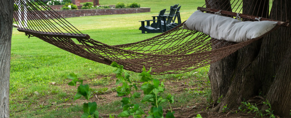 rope hammock hanging between trees offering a quiet space in garden to relax 
