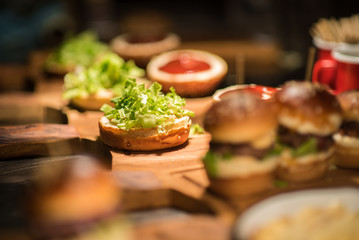 Gourmet Tasty Beef Burgers with Salad Slices on a Wooden Tray inside a bar waiting to be served